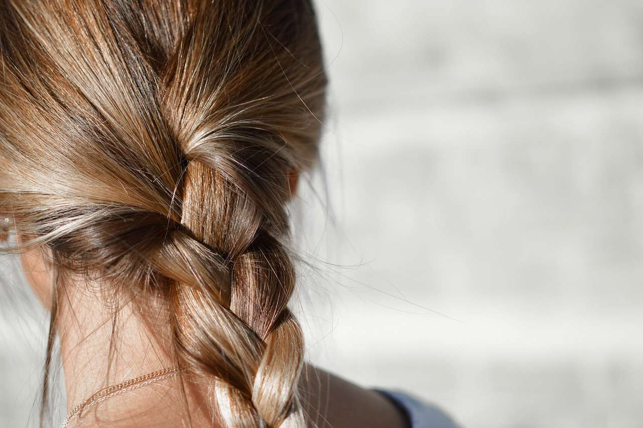 Een close-up van een vrouw met een mooie vlecht in bruin haar, ideaal voor haar inspiratie en styling tips.